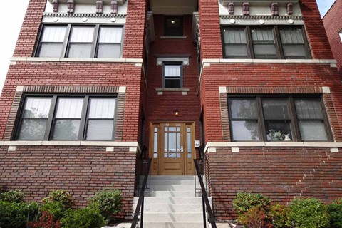 A red brick building with a wooden door and windows.