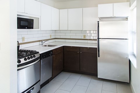 A kitchen with white cabinets and a stainless steel refrigerator.