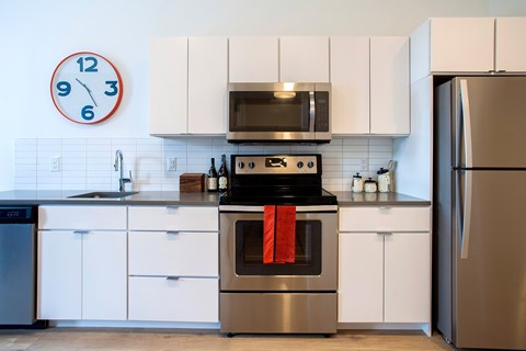 A modern kitchen with a stainless steel oven and white cabinets.