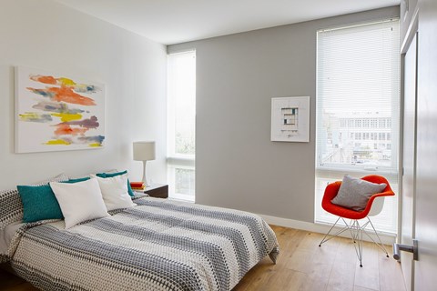 A bedroom with a bed, a chair, and a painting on the wall.