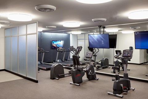 A gym with exercise equipment and a television screen.