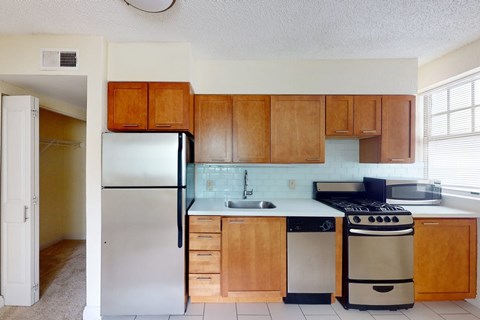 A kitchen with wooden cabinets and a black refrigerator.