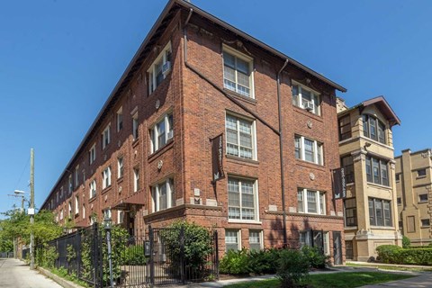 A red brick building with a black fence in front.