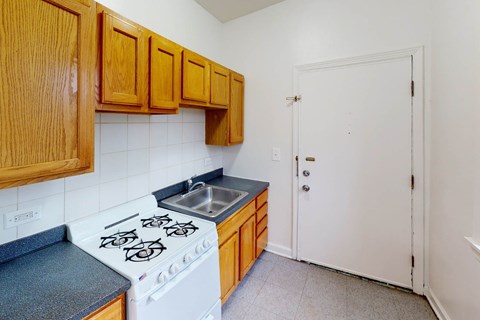 A kitchen with a white stove top oven and wooden cabinets.