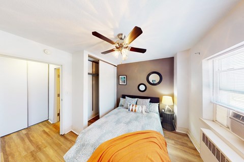 A bedroom with a bed, a ceiling fan, and a window.