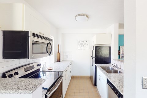 A kitchen with black and white appliances and a calendar on the wall.