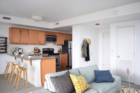 A kitchen with a bar and a couch with two pillows.