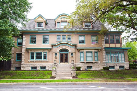 A large, two-story house with a green lawn in front.