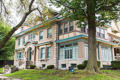 A large, old house with a tree in front of it.