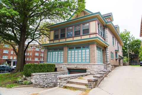 A two-story house with a green roof and stone steps leading to the front door.