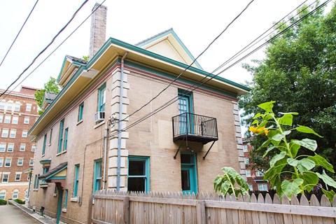 A house with a balcony and a fence in front of it.