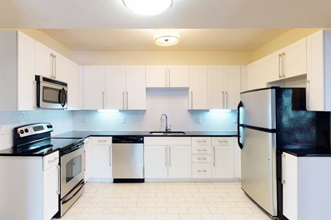 A kitchen with white cabinets and black appliances.