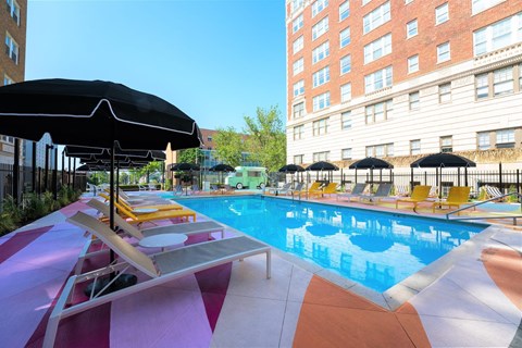 A pool with a striped floor and a black umbrella.