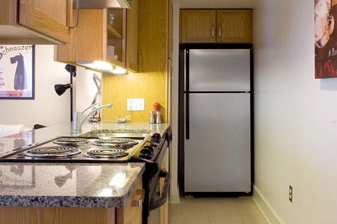 A kitchen with a granite counter top and a fridge.