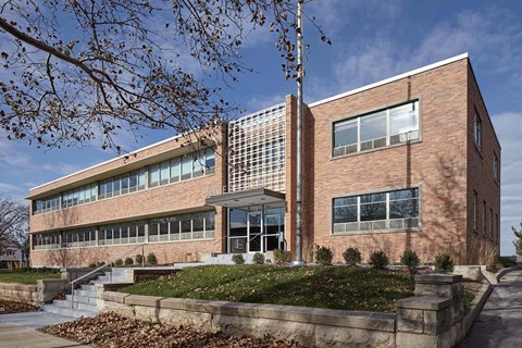 A red brick building with a glass window and a metal grate on the side.
