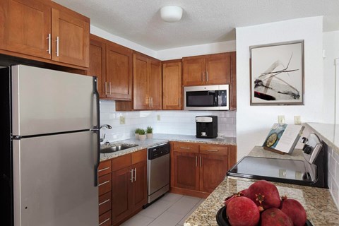 A kitchen with a refrigerator, microwave, and sink.