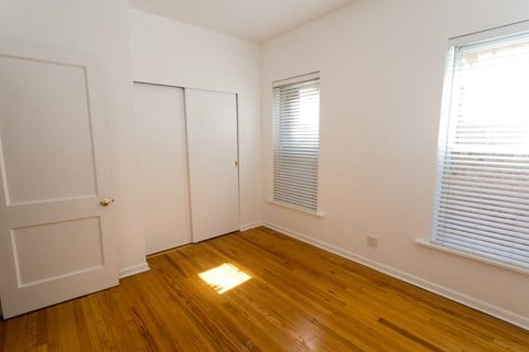 A room with a wooden floor and a window with blinds.