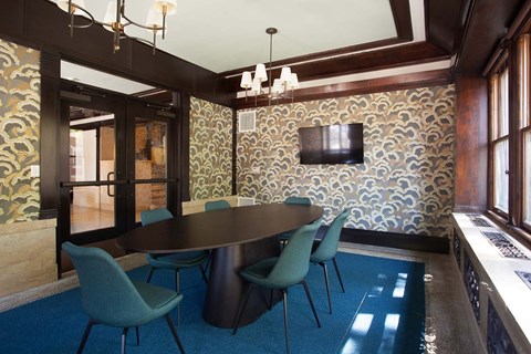 A dining room with a patterned wallpaper and a dark wooden table.