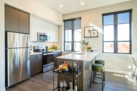 A modern kitchen with a stainless steel refrigerator and a bar area.
