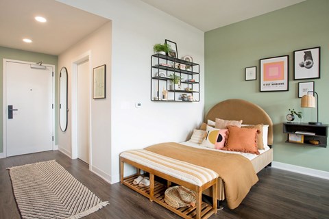 A bedroom with a bed, a rug, and a wall-mounted shelf.