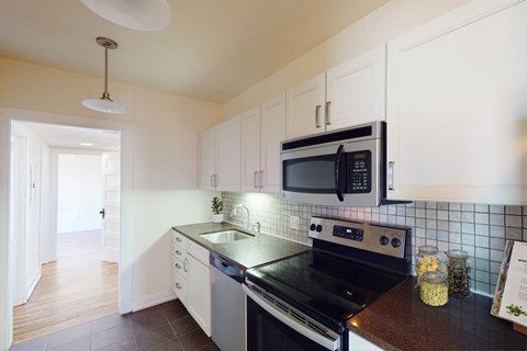 A modern kitchen with a black stove top oven and white cabinets.