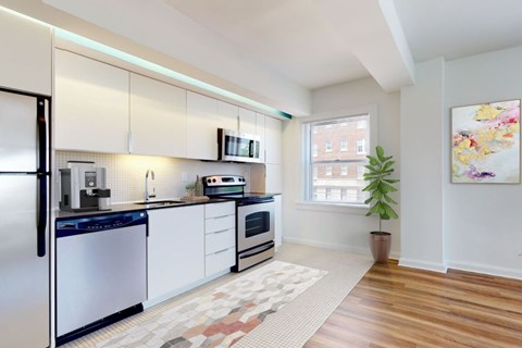 A kitchen with white cabinets and a black fridge.