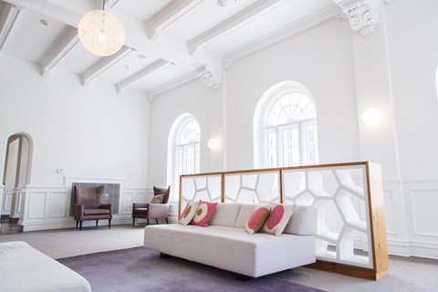 A white bedroom with a bed and a chair.