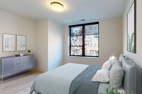A bedroom with a bed, nightstand, and a window with a view of a city.