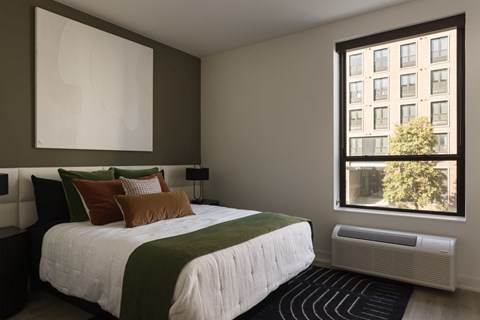 A bedroom with a large bed and a window overlooking a building.