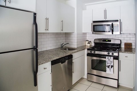 A kitchen with a refrigerator, microwave, oven, and dishwasher.