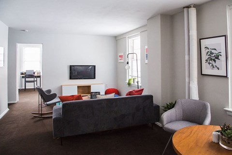 A living room with a grey couch, a chair, a table, and a television.