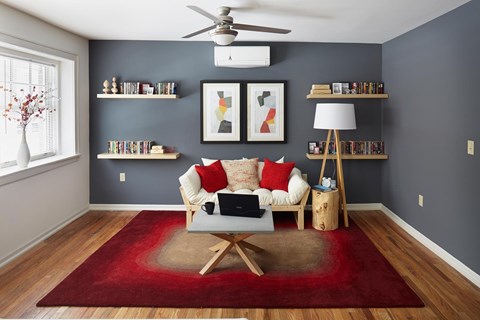 A living room with a red rug and a white couch.