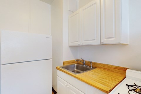 A white refrigerator is in a kitchen with a wooden counter top.