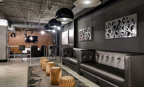 A modern living room with a dark grey sofa and wooden stumps on the floor.