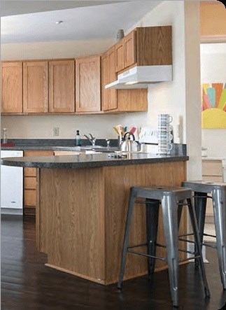 A kitchen with wooden cabinets and a bar stool.