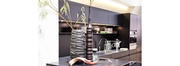 A tall vase with a plant in it is on a counter.