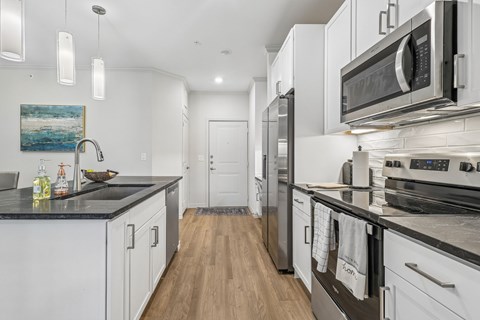 A modern kitchen with white cabinets and stainless steel appliances.