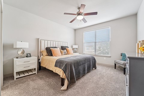 A bedroom with a bed, nightstand, and window.