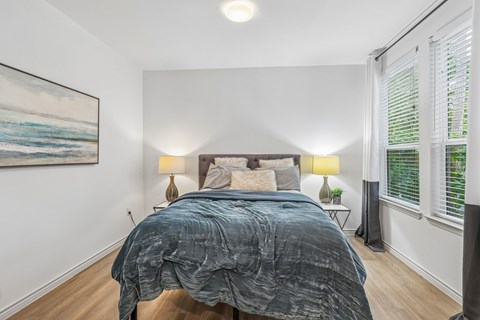 A bedroom with a large bed and a painting on the wall.