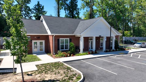 A small white building with a brick facade and a parking lot in front.
