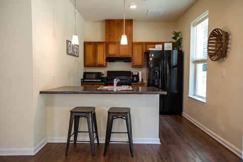 A kitchen with a black refrigerator and wooden cabinets.