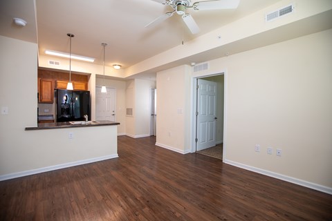 A kitchen with a refrigerator, a ceiling fan, and a wooden floor.