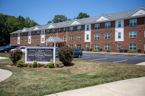A large brick building with a sign in front that says King William Place.