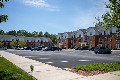 A parking lot in front of a row of apartment buildings.