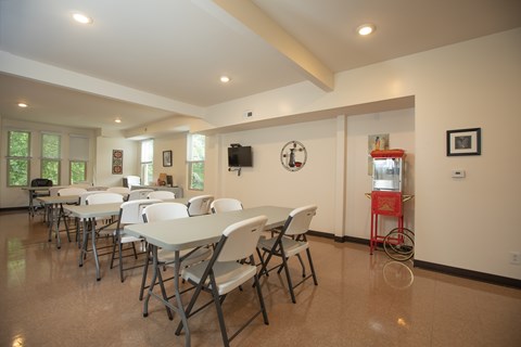 A room with tables and chairs and a clock on the wall.