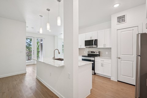 A kitchen with white cabinets and a wooden floor.