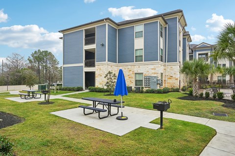 A blue umbrella is on a picnic table in front of a building.