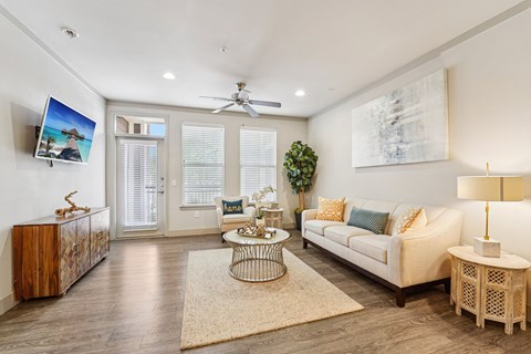A living room with a white couch, a wooden cabinet, a coffee table, and a painting on the wall.