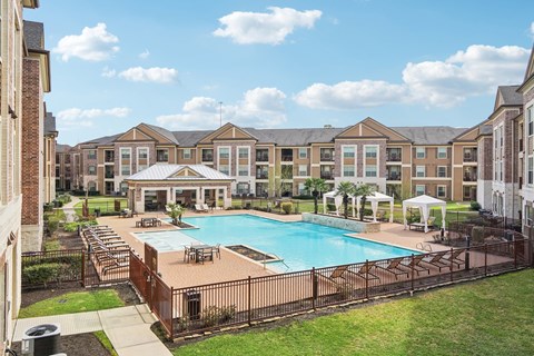 A large swimming pool surrounded by a fence and a building in the background.