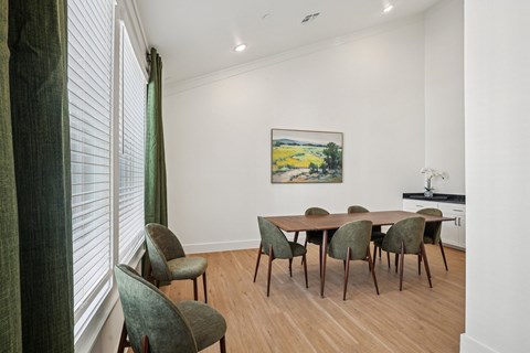 A dining room with a table and chairs and a painting on the wall.